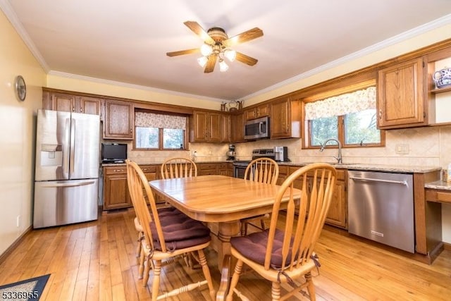 dining area featuring sink, crown molding, light hardwood / wood-style flooring, and ceiling fan