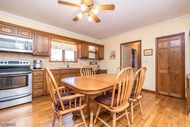 dining space with crown molding, ceiling fan, light hardwood / wood-style floors, and sink