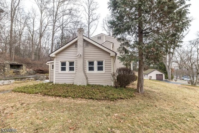 view of home's exterior with a garage, an outdoor structure, and a yard