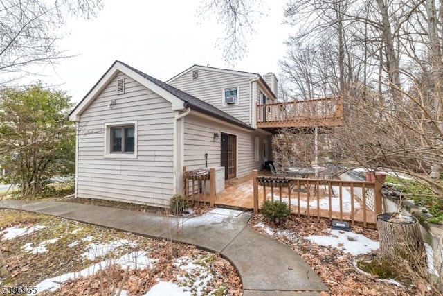 snow covered rear of property with a deck