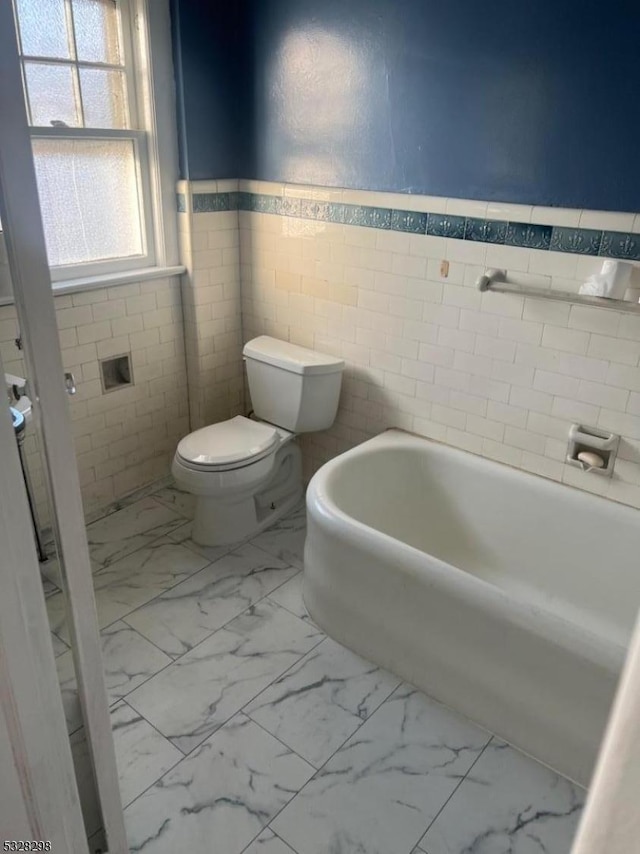 bathroom with tile walls, a bath, and toilet