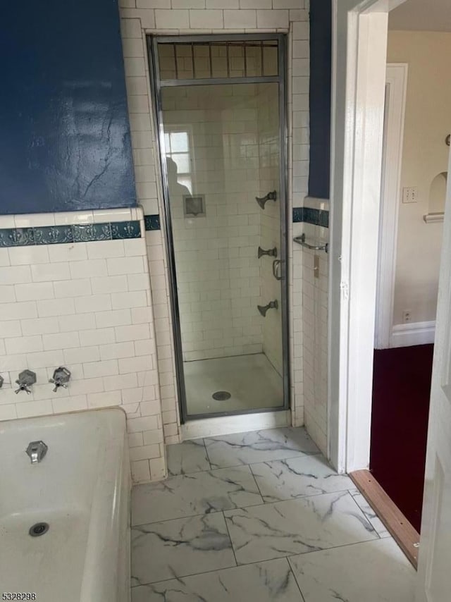 bathroom with an enclosed shower and tile walls