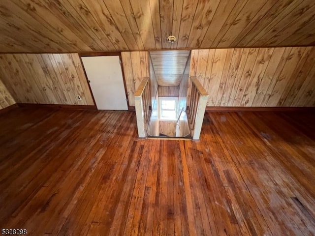 additional living space featuring dark wood-type flooring, wooden ceiling, and wood walls