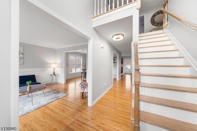 entrance foyer with a towering ceiling, ornamental molding, and light hardwood / wood-style floors