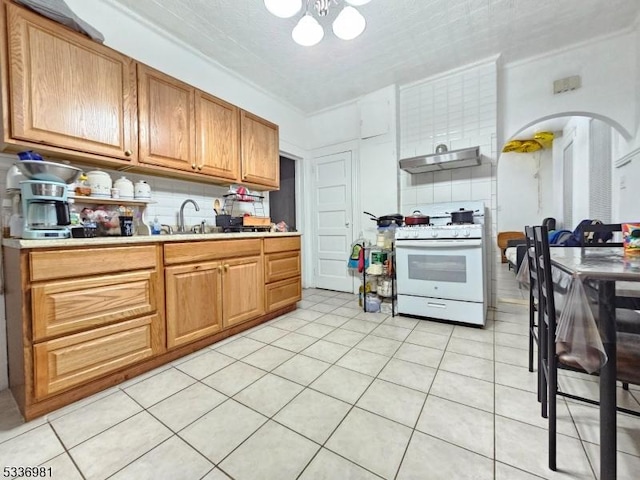 kitchen featuring sink, gas range gas stove, an inviting chandelier, light tile patterned floors, and backsplash