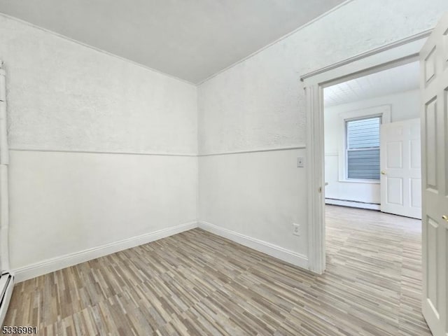 spare room with a baseboard radiator and light hardwood / wood-style flooring