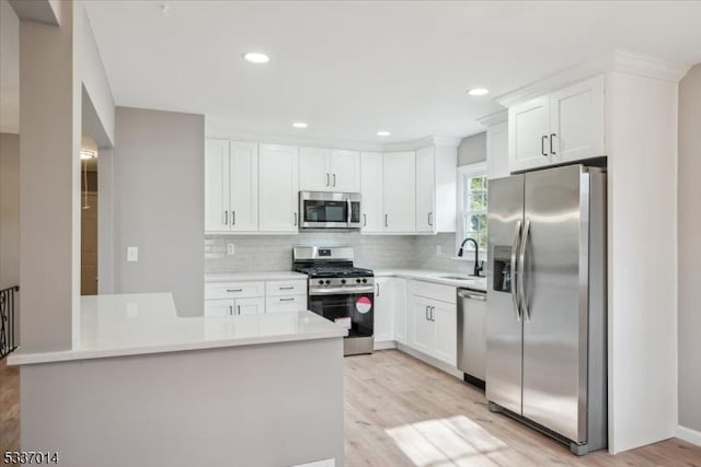 kitchen featuring tasteful backsplash, stainless steel appliances, light hardwood / wood-style flooring, and white cabinets