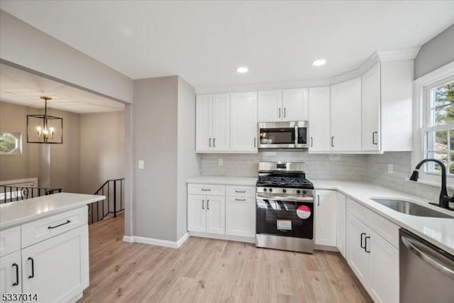 kitchen with white cabinetry, stainless steel appliances, sink, and light hardwood / wood-style flooring