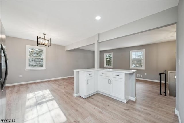 kitchen featuring white cabinetry, light hardwood / wood-style flooring, an inviting chandelier, and decorative light fixtures