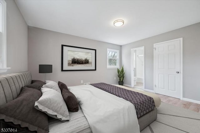 bedroom featuring ensuite bath and light wood-type flooring