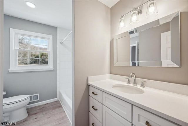 full bathroom featuring tiled shower / bath combo, vanity, wood-type flooring, and toilet