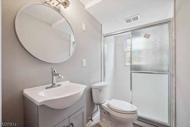 bathroom featuring vanity, a shower with shower door, and toilet