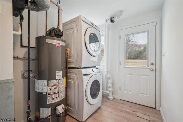 clothes washing area featuring stacked washer / dryer, water heater, and light wood-type flooring