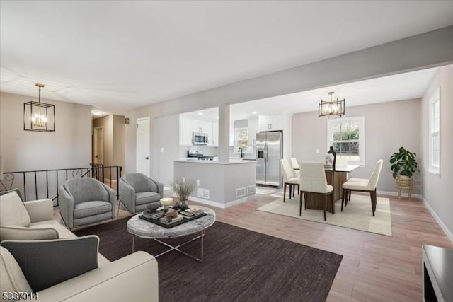 living room featuring a notable chandelier, light hardwood / wood-style flooring, and sink