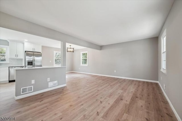 unfurnished living room featuring a notable chandelier and light hardwood / wood-style flooring