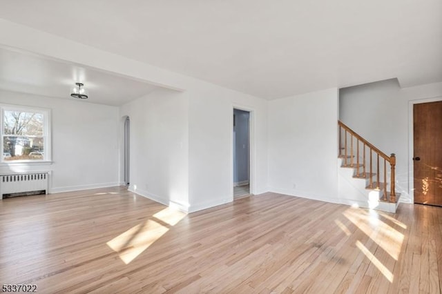 unfurnished living room featuring radiator and light wood-type flooring