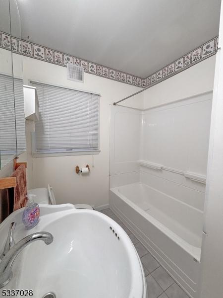 bathroom featuring tile patterned floors,  shower combination, and sink