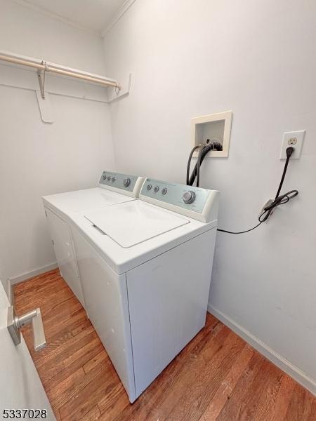 laundry room featuring crown molding, light hardwood / wood-style floors, and washing machine and clothes dryer