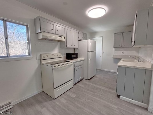 kitchen with gray cabinets, sink, white appliances, and light hardwood / wood-style floors