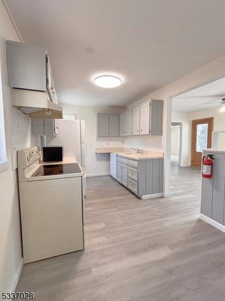 kitchen with gray cabinets, ceiling fan, white range with electric cooktop, tasteful backsplash, and light hardwood / wood-style floors