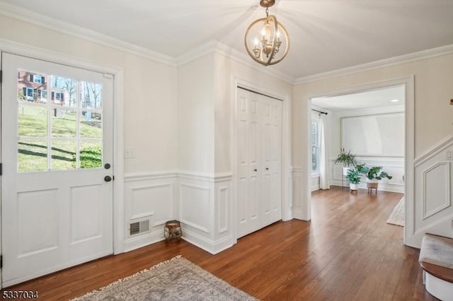 entryway featuring ornamental molding, dark wood-type flooring, and a chandelier