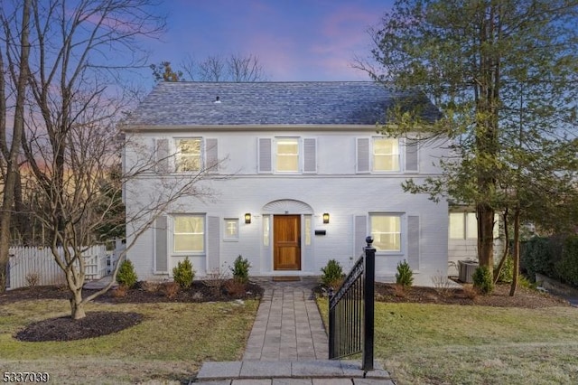 colonial inspired home with a yard and central air condition unit