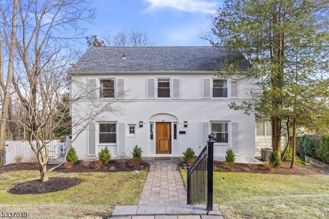 colonial house featuring a front lawn and central air condition unit