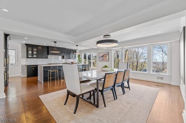 dining area featuring crown molding, dark wood-type flooring, and a tray ceiling