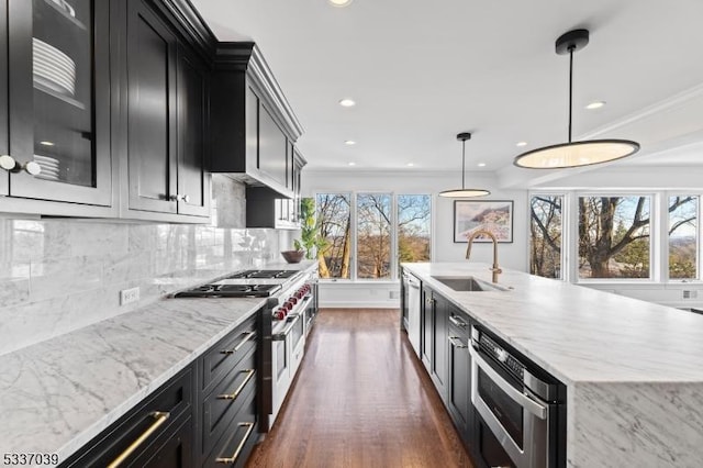 kitchen featuring dark wood-type flooring, sink, tasteful backsplash, hanging light fixtures, and stainless steel appliances