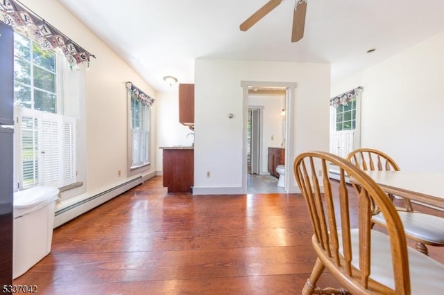 dining space featuring a baseboard radiator, wood-type flooring, a ceiling fan, and baseboards