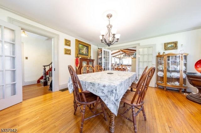 dining area featuring crown molding, baseboards, a notable chandelier, and light wood finished floors