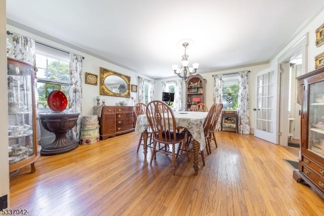 dining space with ornamental molding, an inviting chandelier, and wood finished floors