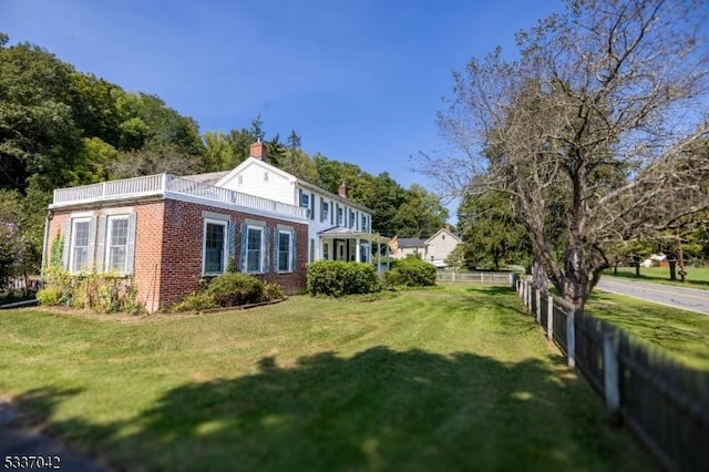 exterior space featuring a yard, brick siding, fence, and a chimney