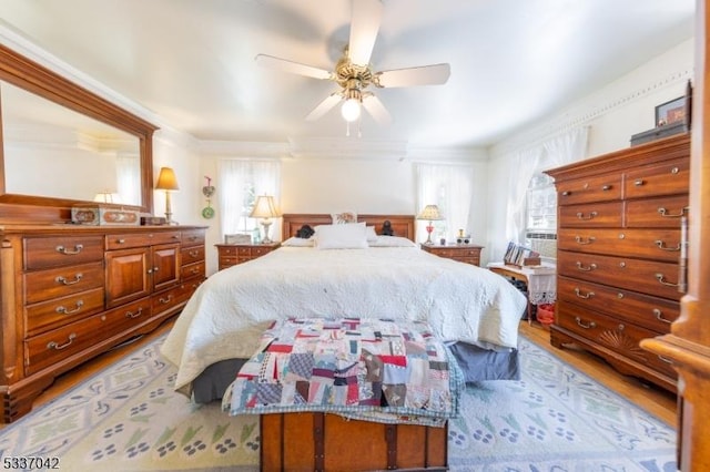 bedroom with crown molding, multiple windows, ceiling fan, and wood finished floors