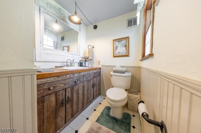 bathroom featuring toilet, vanity, visible vents, and wainscoting