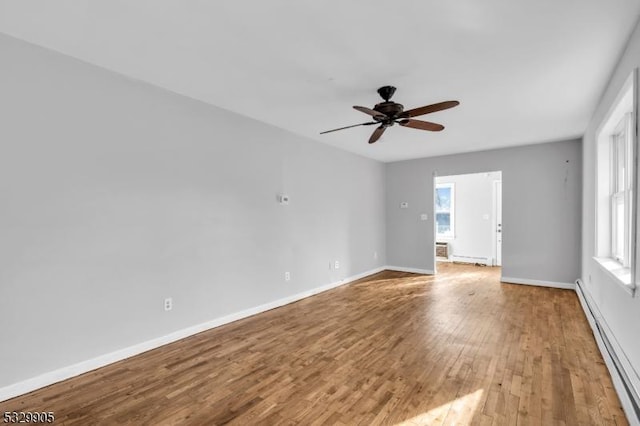 unfurnished room with a baseboard heating unit, light hardwood / wood-style flooring, a healthy amount of sunlight, and ceiling fan