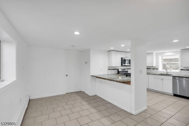 kitchen featuring sink, appliances with stainless steel finishes, white cabinetry, dark stone countertops, and tasteful backsplash