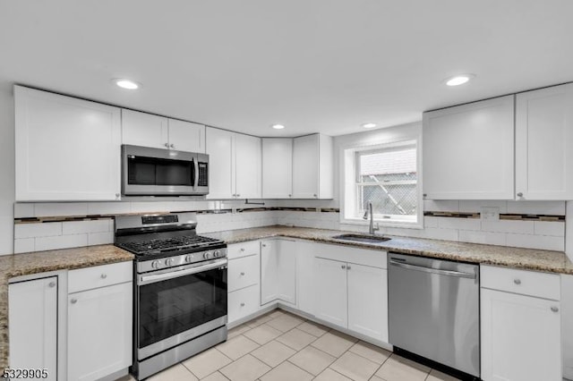 kitchen featuring stainless steel appliances, sink, white cabinets, and decorative backsplash