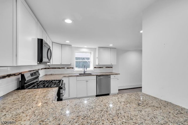 kitchen with sink, appliances with stainless steel finishes, white cabinetry, light stone countertops, and decorative backsplash