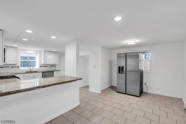 kitchen featuring sink, appliances with stainless steel finishes, tasteful backsplash, white cabinets, and dark stone counters