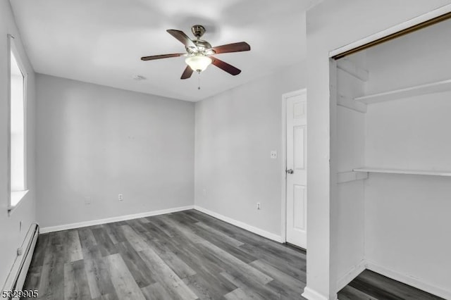 unfurnished room featuring baseboard heating, ceiling fan, and dark hardwood / wood-style floors