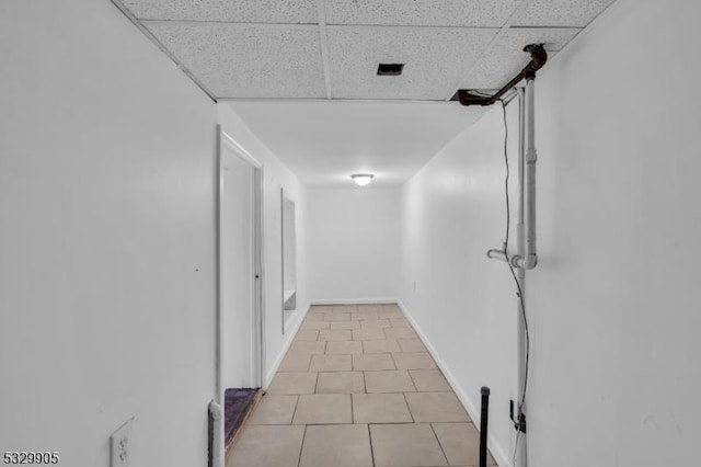 hallway with a paneled ceiling and light tile patterned floors