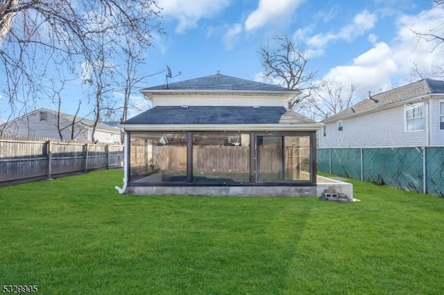 rear view of house featuring a lawn and a sunroom