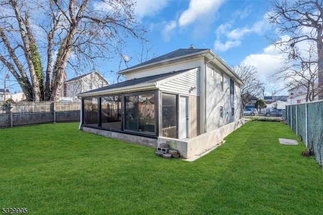 rear view of house featuring a yard and a sunroom