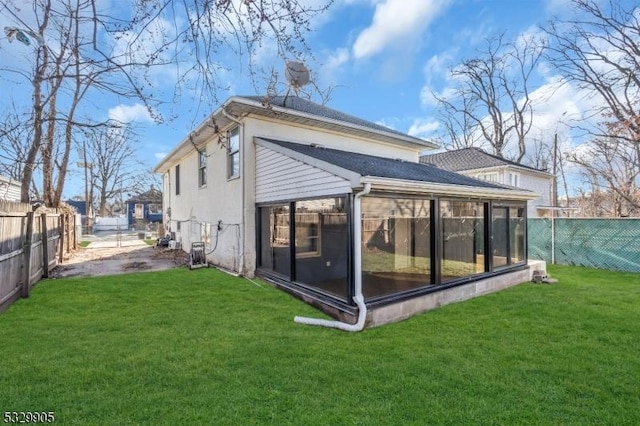 rear view of house featuring a yard and a sunroom