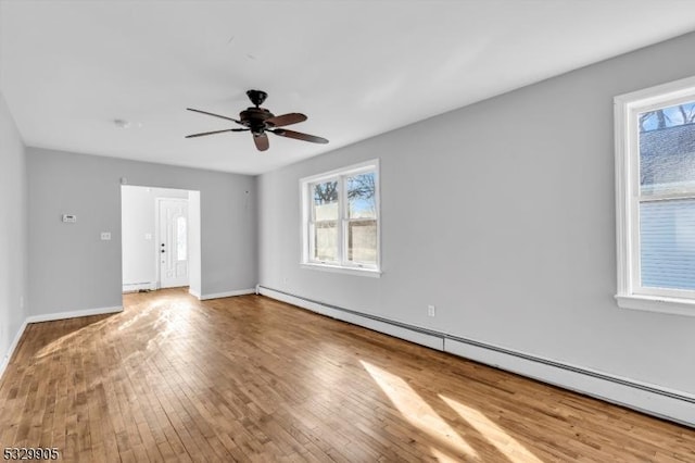 unfurnished room with hardwood / wood-style flooring, a healthy amount of sunlight, a baseboard heating unit, and ceiling fan