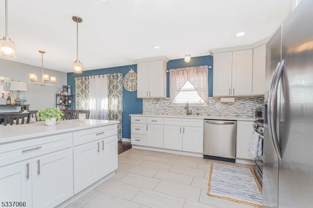 kitchen featuring hanging light fixtures, sink, white cabinets, and appliances with stainless steel finishes