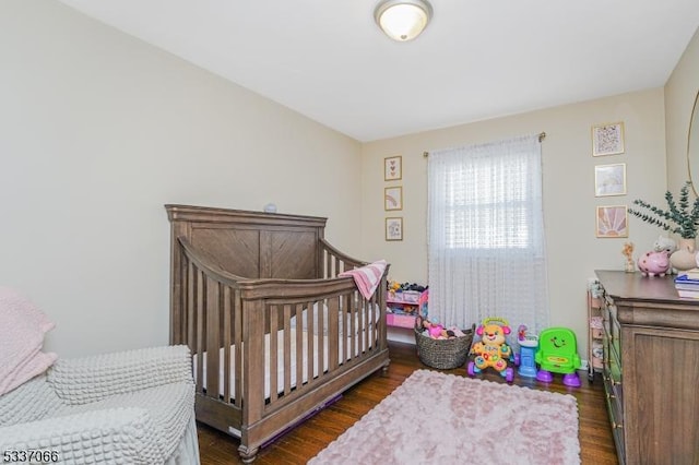 bedroom featuring dark hardwood / wood-style floors and a nursery area