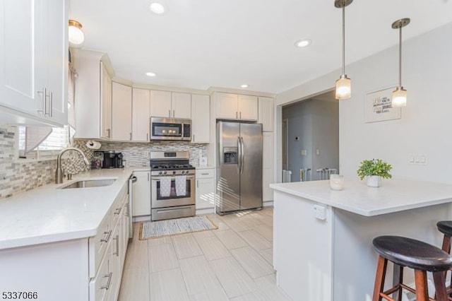 kitchen featuring white cabinetry, stainless steel appliances, decorative light fixtures, and sink