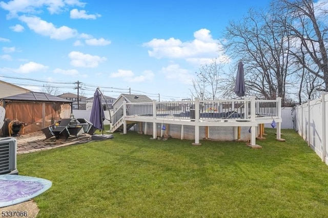 rear view of house with a wooden deck, central AC, and a lawn